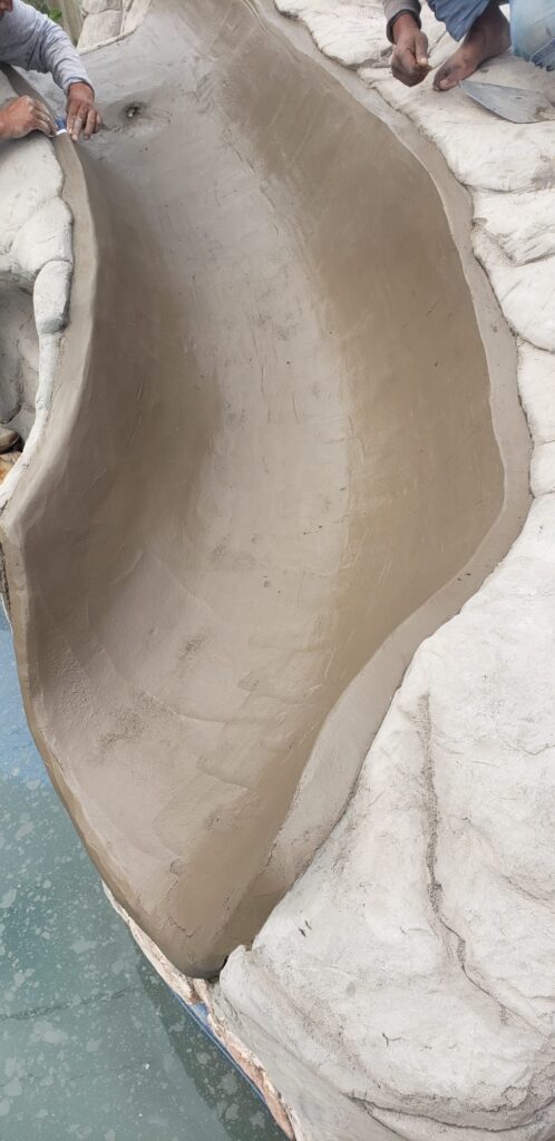 Craftsmen hand-shaping the concrete channel of a custom rock pool slide